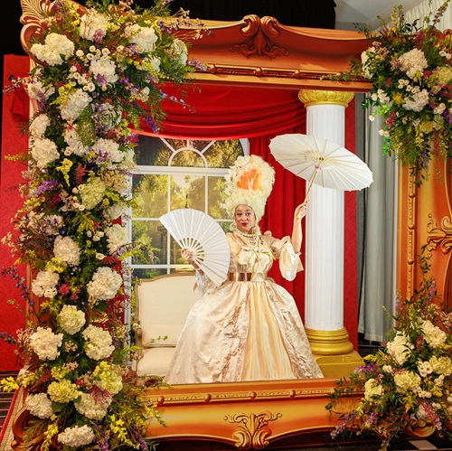 Woman dressed in Marie Antoinette style gown surrounded by flowers