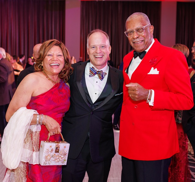 Three people in red-themed formal dress